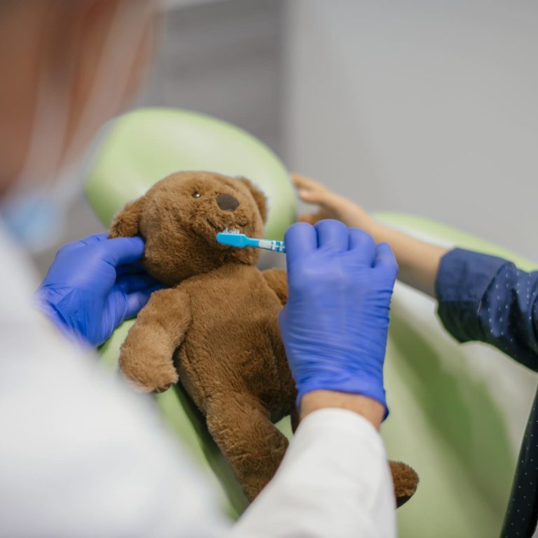 Child at dentists with teddy bear playing with toothbrush. Shadow DOF. Developed from RAW; retouched with special care and attention; Small amount of grain added for best final impression. 16 bit Adobe RGB color profile.