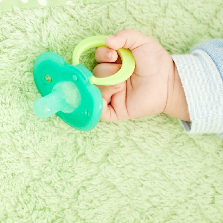 Baby's,Cute,Little,Hand,And,Plastic,Baby,Soother,Pacifier,On