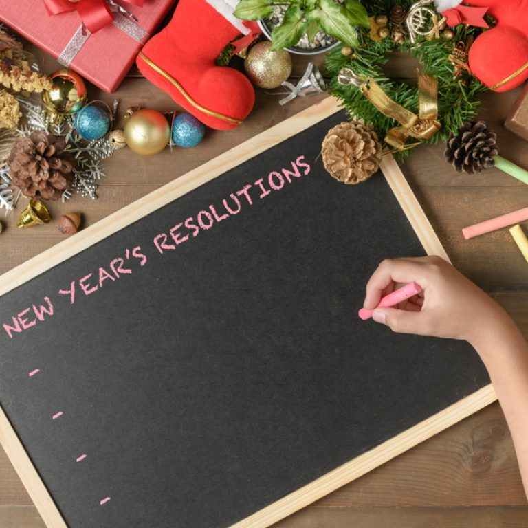 Kid,Writing,New,Year,Resolution,On,Black,Board,With,Decorations
