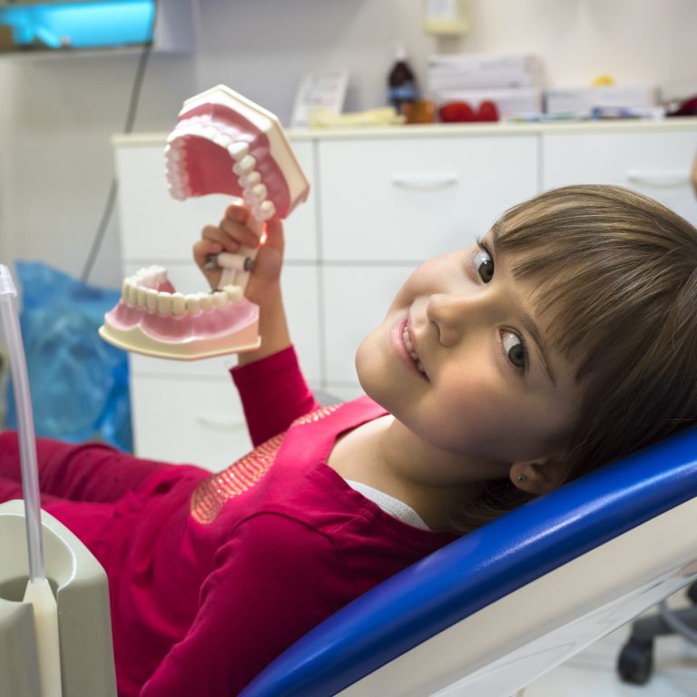 A girl in a dentist office is showing her jaws. Medicine, dentistry and health care.