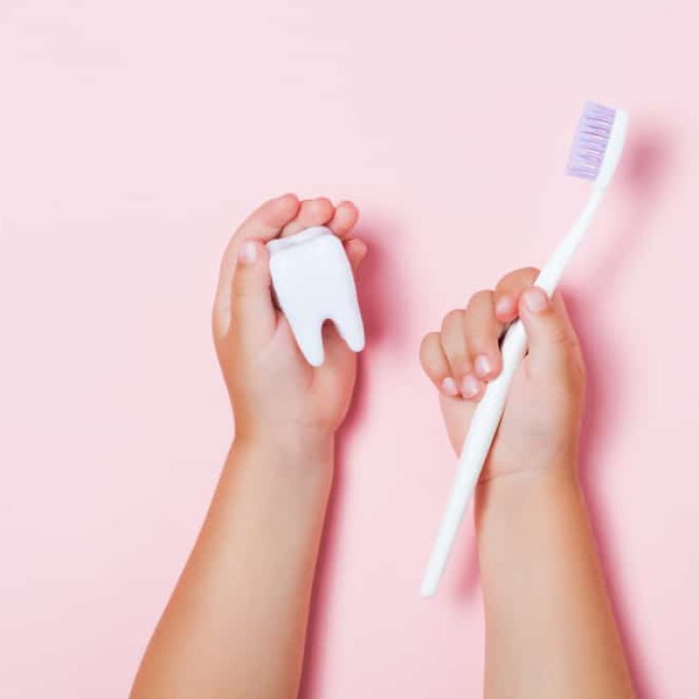 Child's,Hands,Holding,Big,Tooth,And,Toothbrush,On,Pink,Backgroubd.