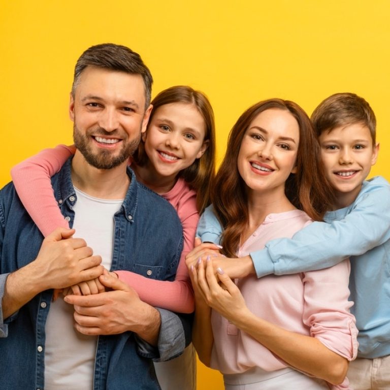 Cheerful,Caucasian,Family,Of,Four,Posing,Together,Against,Yellow,Background,